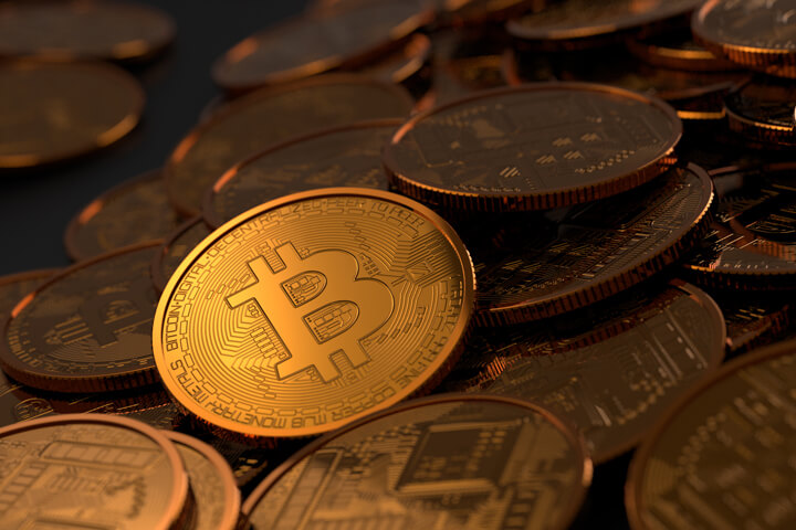 Large pile of Bitcoins with light focused primarily on one coin
