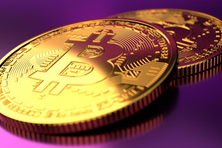 Two Bitcoins with focus on front coin with hard light and fushia background