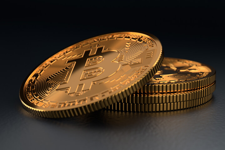 Small stack of Bitcoins with one tipped toward camera on dark background