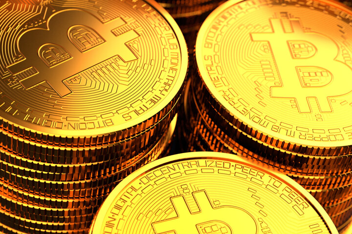 Close-up photo of three stacks of Bitcoins with bright golden lighting