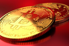 Two Bitcoins on red background with hard light on the coin closest to the camera