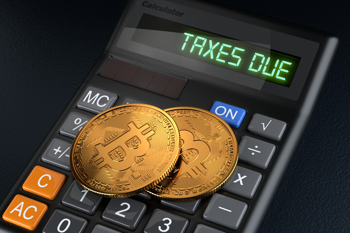 Two Bitcoins laying on calculator with LCD displaying Taxes Due concept for cryptocurrency tax issues
