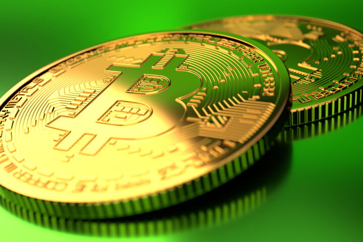 Two Bitcoins on green background with hard spot light