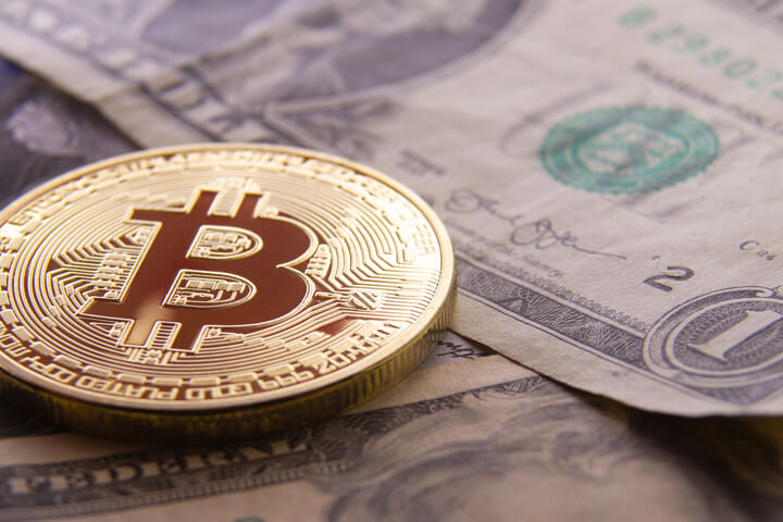 Free photo of a bitcoin on dollar bills