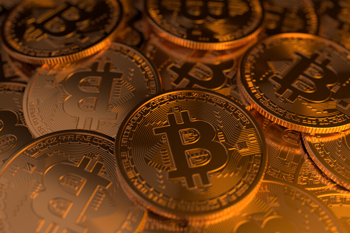 Pile of Bitcoins scattered randomly with soft golden lighting to right