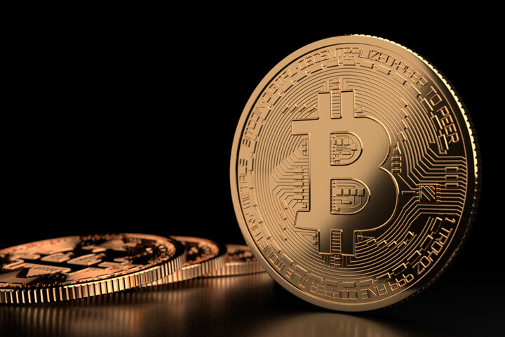 Bitcoin standing on edge on black glossy surface with reflection