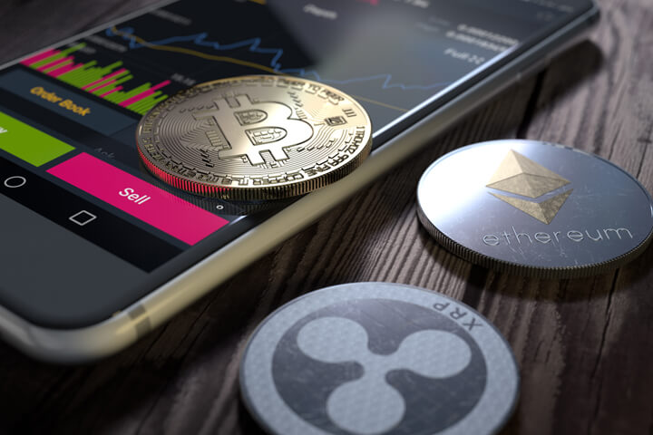Bitcoin, Ethereum, and XRP coin with mobile phone showing stock exchange trading data