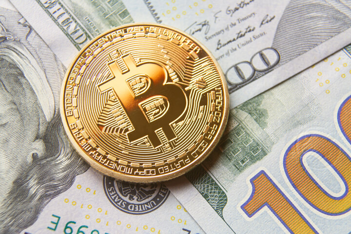 Bitcoin on scattered 100 dollar bills