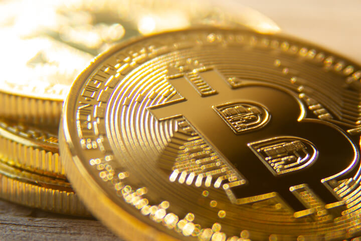 Bitcoin leaning against stack of bitcoins with soft backlight and bokeh