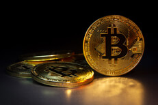 Bitcoin on edge with others Bitcoin standing on edge with four scattered Bitcoins and dark background