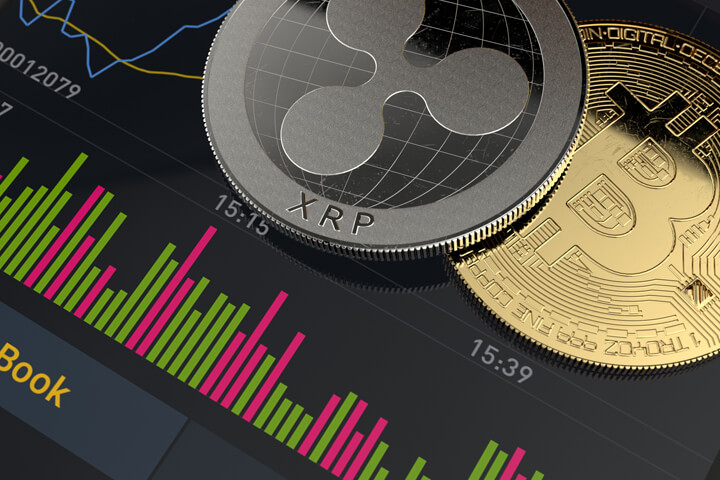 Bitcoin and Ripple XRP coins on mobile phone screen showing stock market trading app