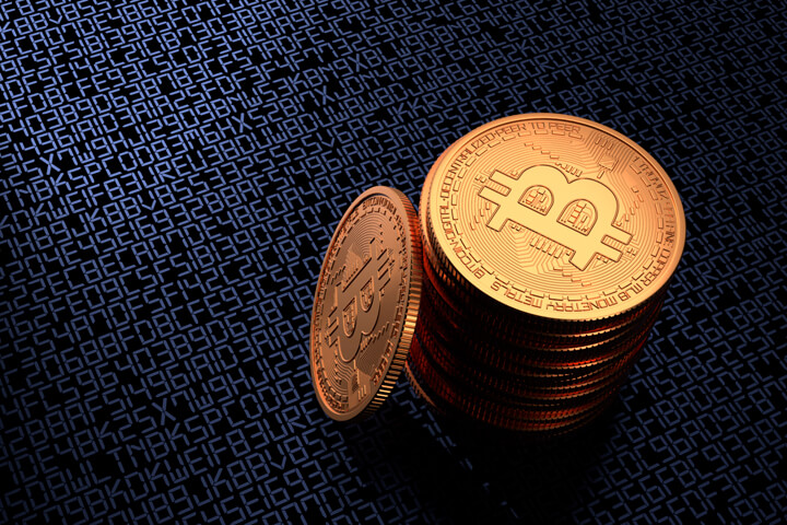 Stack of Bitcoins on dark background with blue illuminated digital key or blockchain