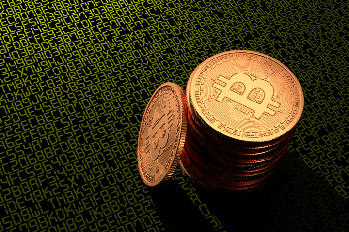 Stack of Bitcoins on dark background with green illuminated digital key or blockchain