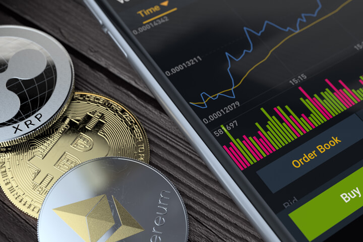 Bitcoin, Ethereum, and Ripple XRP coins next to iPhone showing Binance trading app data
