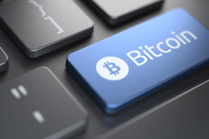 Computer keyboard with blue Bitcoin key highlighted by spotlight from behind