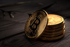 Bitcoins with glasses on wood Stack of Bitcoins on rough weathered wood with reading glasses in background