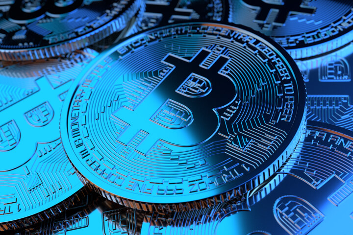 Pile of random Bitcoins illuminated by two blue lights symbolizing price decline or a bear market