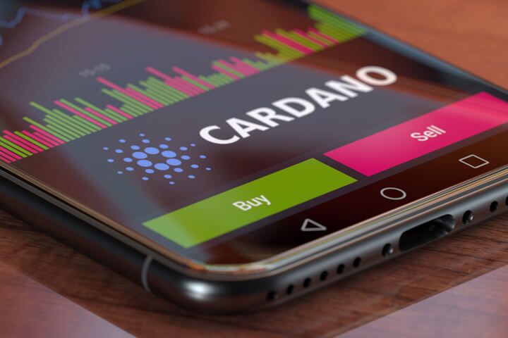 Cardano exchange app on iPhone X screen showing Cardano logo, trading volume, and option to buy or sell cryptocurrency