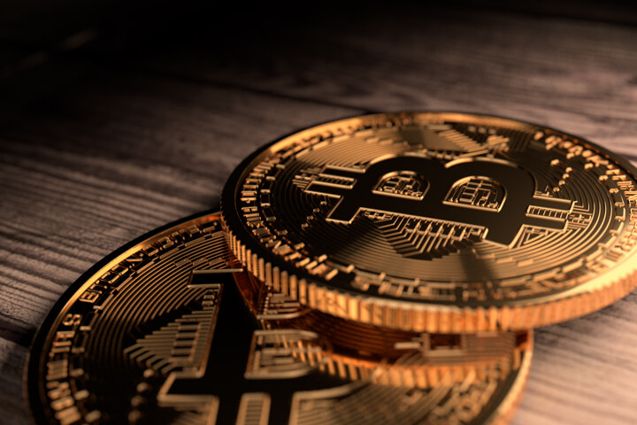 Close up photo of two Bitcoins placed on rough weathered wood plank background