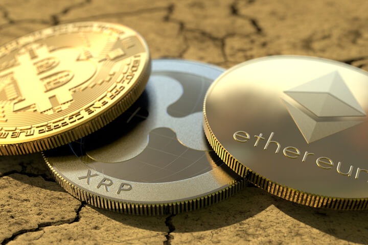 Bitcoin, Ripple, and Ethereum coins on parched, cracked dirt
