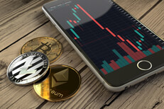 Crypto coins with iPhone candlestick chart Bitcoin, Ethereum, and Litecoin coins next to iPhone showing candlestick stock chart