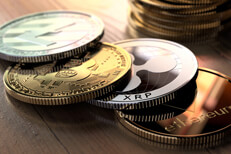 Crypto coins with coin stack Bitcoin, Ripple, Litecoin, and Ethereum coins in front of stack of Bitcoins