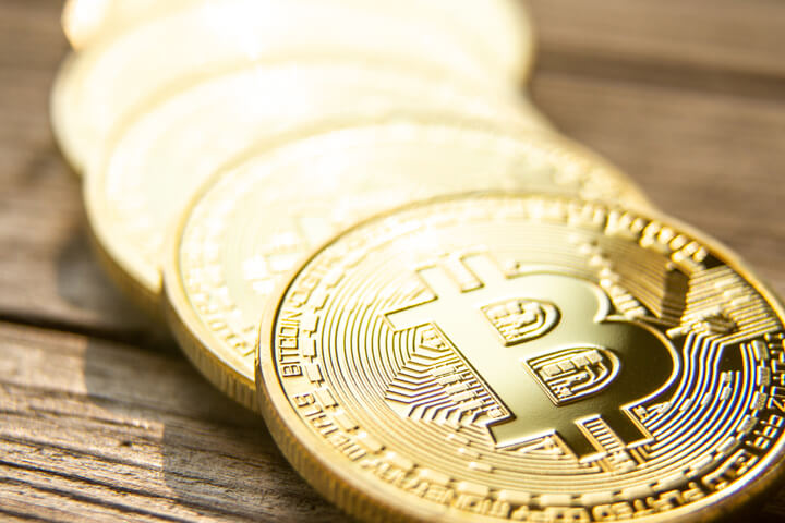 Curved row of five bitcoins with short depth of field