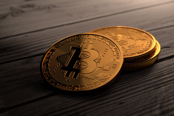 Four Bitcoins placed on weathered planks with top right corner lighting