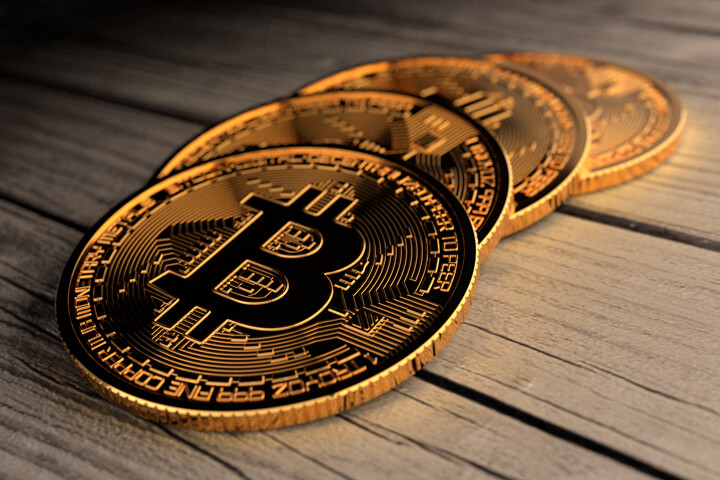 Four Bitcoins laid in a row on weathered wood planks