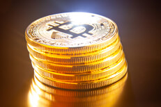 Leaning stack of bitcoins Leaning stack of bitcoins on reflective textured surface with light flare