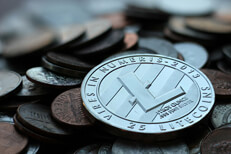 Litecoin on currency pile Photo of Litecoin cryptocurrency coin on top of an assorted pile of U.S. currency coins