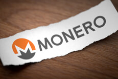 Monero logo on torn scrap of paper Monero altcoin cryptocurrency logo printed on torn piece of scrap paper on woodgrain surface