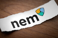 Nem logo on torn scrap of paper Nem altcoin cryptocurrency logo printed on torn piece of scrap paper on woodgrain surface