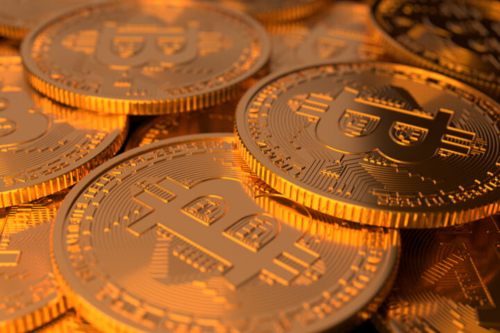 Closer viewpoint of large random pile of Bitcoins illuminated with soft golden light from top and side
