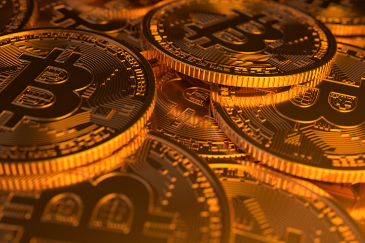 Closer viewpoint of large random pile of Bitcoins illuminated with soft golden light from side