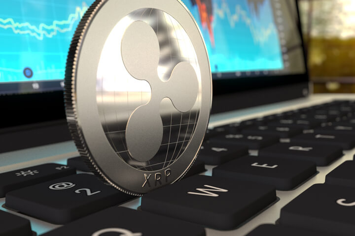 Ripple cryptocurrency coin standing on edge on laptop