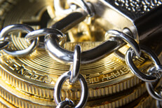 Close up photo of padlock and chain around Bitcoins Close up photo of a stack of Bitcoins secured by chains and a padlock