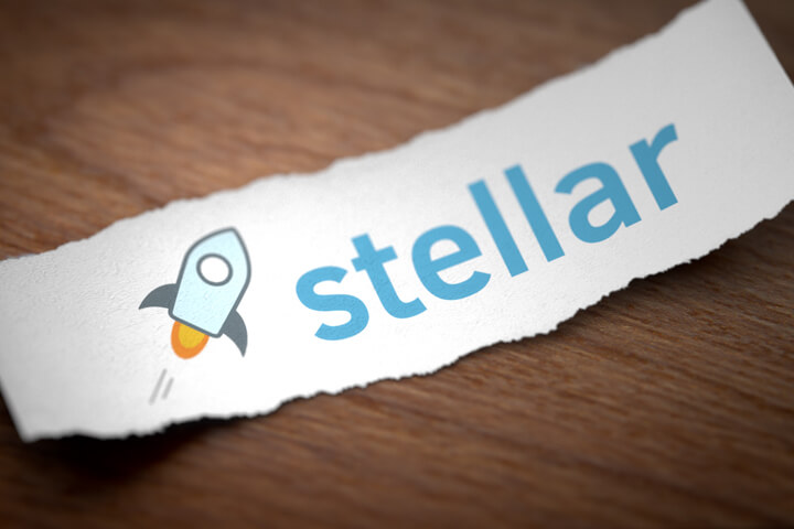 Stellar altcoin cryptocurrency logo printed on torn piece of scrap paper on woodgrain surface
