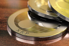 Three Ripple coins Three Ripple cryptocurrency tokens laying on wood desk with window reflection