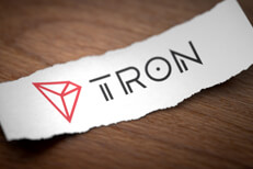 Tron logo on torn scrap of paper Tron altcoin cryptocurrency logo printed on torn piece of scrap paper on woodgrain surface