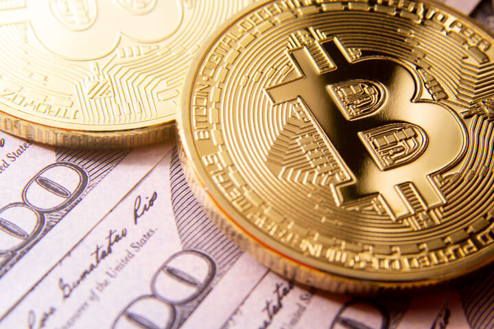 Two bitcoins on fanned 100 dollar bills