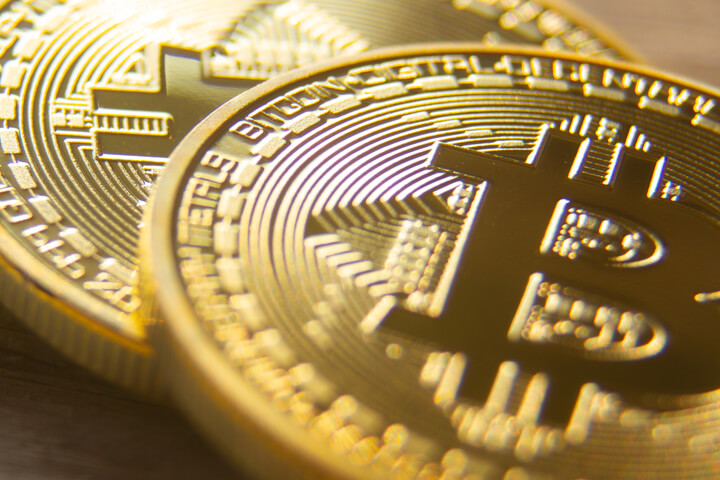 Two bitcoins laid on wood background with shallow depth of field