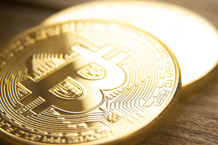 Two bitcoins laid on wood background with shallow depth of field and highlight