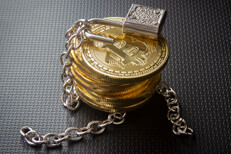 Stack of insecure Bitcoins Stack of Bitcoins with unlocked padlock and loose chains on dark carbon fiber background
