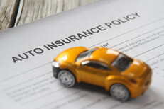 Auto insurance policy on wood plank background with small toy car