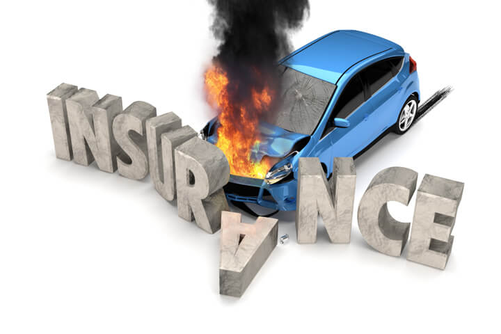 Comprehensive insurance claim concept image of car on fire crashed into large stone insurance letters