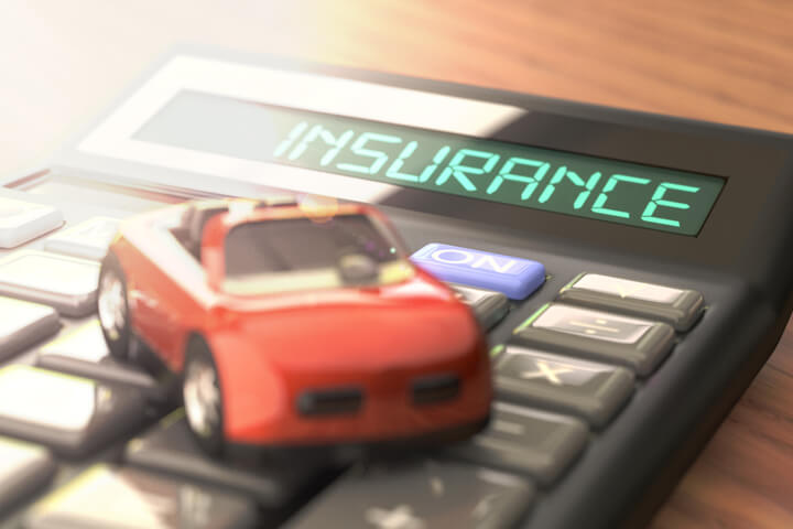 Wood table with insurance calculator and toy car with strong light flare effect