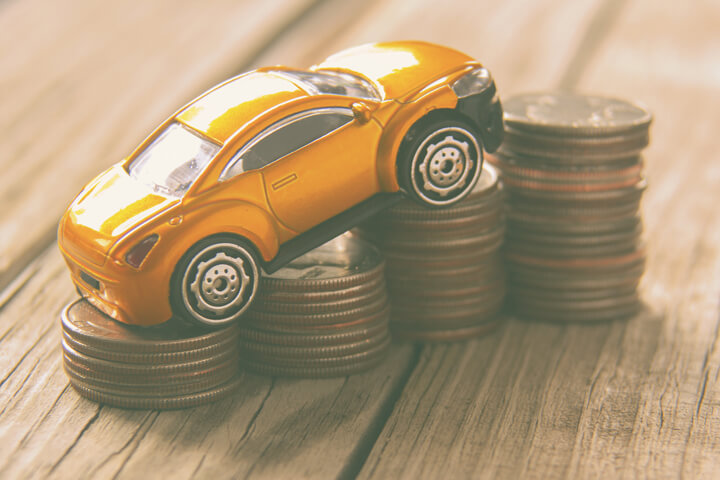 Vintage photo of small toy car climbing increasing stacks of coins
