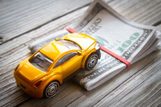 Toy car climbing folded bills Yellow toy car climbing folded 100 dollar bills car insurance or automotive costs concept photo
