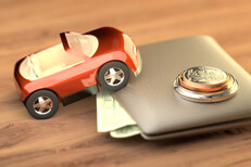 Toy car climbing wallet with dollar bills protruding and coins